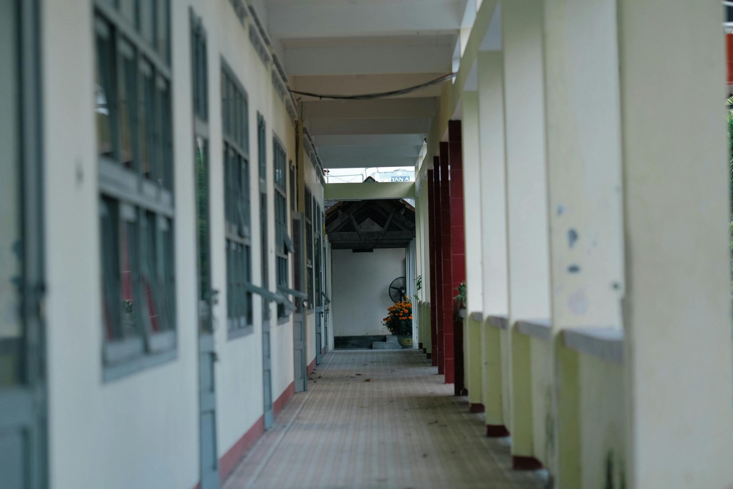 A serene, empty school corridor with soft natural lighting and open windows.